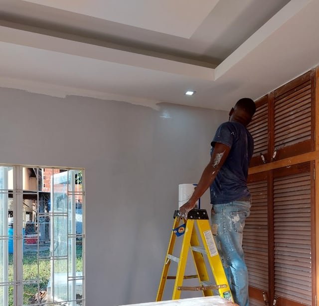 A Jamaal's Industrial worker repainting an interior wall as part of a building maintenance programme